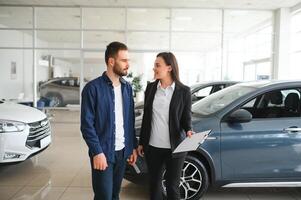 freundlich, lächelnd weiblich Verkäufer zeigen Marke Neu Auto zu ein Kunde während Stehen im Auto Salon foto