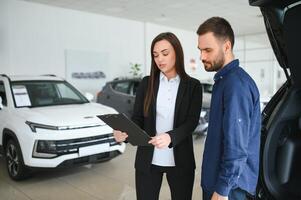 lächelnd Auto Verkäufer Stehen im Auto Salon mit Kunde und zeigen um Autos auf Verkauf foto