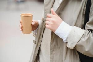 schön stilvoll Frau haben gut Mode Kleider Gehen auf Straße und Trinken etwas Kaffee im Tasse wegbringen mit gut Sommer- Stimmung in der Nähe von Straße Cafe. foto