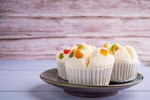 Seite Aussicht von thailändisch gedämpft Cupcakes gekrönt mit trocken Obst auf ein Teller mit hölzern Mauer Hintergrund. Khanom pui fai im thailändisch foto