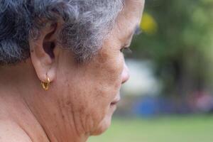 Seite Aussicht von das Gesicht von ein Senior Frau tragen ein golden Ohrring. Konzept von alt Menschen und Gesundheitswesen foto