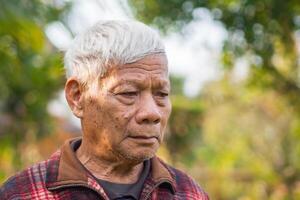 Porträt von ein Senior Mann mit kurz grau Haar suchen Weg während Stehen draußen. Konzept von alt Menschen und Gesundheitswesen foto