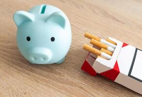 Schweinchen Bank auf Stapel von Zigaretten isoliert. Konzept von Ersparnisse foto