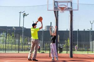 Vater und Tochter spielen Basketball zusammen auf Spielplatz foto