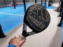 Ukraine Kiew, April 11 2024. Padel Schläger adidas und Padel Ball auf ein Grün Gericht foto