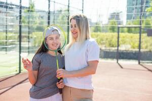 Mutter und Tochter sind spielen Badminton draußen im das Hof auf Sommer- heiß Tag foto