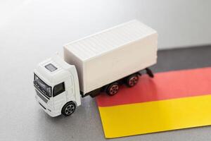 Mini Spielzeug beim Tabelle mit verschwommen Hintergrund. industriell Versand Konzept. Spielzeug LKW, Deutschland Flagge foto