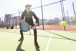 Mann spielen Padel im ein Grün Gras Padel Gericht Innen- hinter das Netz foto