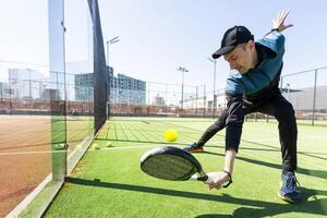 Mann spielen Padel im ein Grün Gras Padel Gericht Innen- hinter das Netz foto