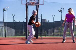 ein glücklich Mutter und Kind Tochter draußen beim Basketball Gericht. foto