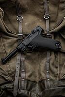 Deutsche Jahrgang 9mm Pistole von das zweite Welt Krieg. Hintergrund von ein alt Segeltuch Militär- Rucksack. foto