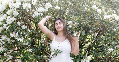 schön jung Frau tragen Weiß Sommer- Kleid umgeben durch Weiß Rhododendron blühen foto