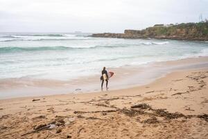 Surfer mit Surfbrett Blick Meer Wellen eilen gegenüber Strand Ufer foto