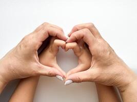 schließen oben von Mitte Alter Frau und Kinder Hände Bildung Herz gestalten auf Weiß Hintergrund. Familie Liebe und Verbindung Konzept. Design zum Gesundheitspflege, Wellness, und Familie Pflege Poster. foto