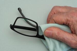 das Hand von ein Mann abwischen Brille. foto