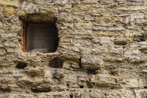 Fragment von ein Antiquität Stein Mauer mit ein eng Fenster. foto