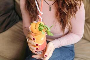 Frau Sitzung auf Couch halten ein trinken foto