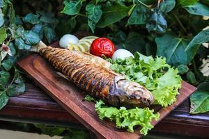 frisch Fisch auf Schneiden Tafel mit Grüner Salat und Tomaten foto
