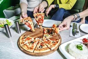 Gruppe von Menschen genießen Pizza beim ein Tabelle foto