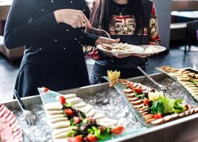 zwei Frauen Stehen zusammen, jeder mit ein Teller von Essen foto