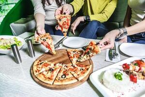 Gruppe von Menschen genießen Pizza beim ein Tisch. foto