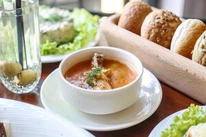 Schüssel von Suppe mit Brot und Salat auf Tabelle foto