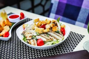 Schüssel von Salat und Glas von Wein auf Tabelle foto