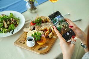 Frau nehmen ein Bild von Essen auf ihr Telefon foto