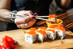 Frau halten Essstäbchen Über ein Teller von Sushi foto