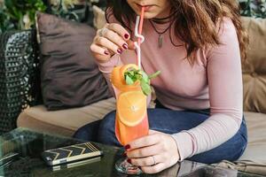 Frau Sitzung auf Couch, Trinken ein Getränk foto