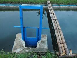 Bewässerung Kanal mit Blau Metall Tür zum Reis Felder foto