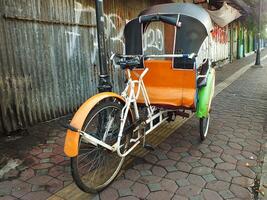 Surakarta, zentral Java, Indonesien April 11, 2024. Jahrgang becak Fahrzeug ist ein traditionell Öffentlichkeit Transport von Indonesien. foto