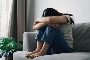 unzufrieden einsam deprimiert Frau ist Sitzung auf das Couch und Abdeckung ihr Gesicht mit ihr Hände foto