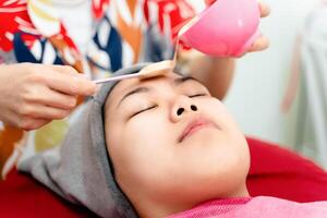 schön jung asiatisch Frau bekommen ein Gesichts- Maske Behandlung beim das Schönheit Salon. Gesichts- Hautpflege. foto