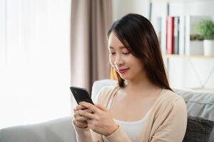 ein Frau ist Sitzung auf ein Couch und suchen beim ihr Zelle Telefon foto