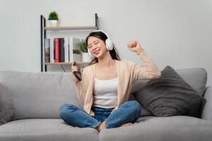 ein Frau ist Sitzung auf ein Couch mit ein Zelle Telefon im ihr Hand foto