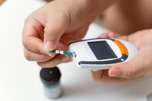 asiatisch Frau Überprüfung Blut Zucker Niveau durch Digital Glucose Meter foto