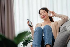 ein Frau ist Sitzung auf ein Couch mit ein Zelle Telefon im ihr Hand foto