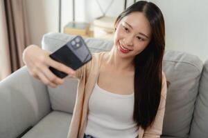 ein Frau ist Sitzung auf ein Couch und nehmen ein Selfie mit ihr Zelle Telefon foto