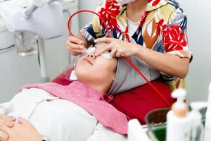 Kosmetikerinnen ausführen Ultraschall Gesichts- Verfahren mit Ausrüstung. Frau bekommen Gesichts- Massage. foto