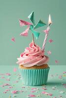 ein Rosa und Grün Cupcake mit ein Spinnen oben auf oben und ein zündete Kerze auf das Seite foto