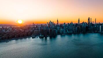 Orange Licht von Rahmen Sonne leuchten das Wolkenkratzer und Hochhaus Gebäude im Neu York Landschaft. oben Aussicht auf das Metropole von über das Osten Fluss. foto