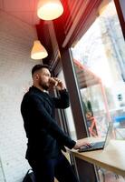 jung erfolgreich Mann sitzen im das Cafe. gut aussehend zuversichtlich Geschäftsmann Arbeiten mit Tasse von Kaffee. foto