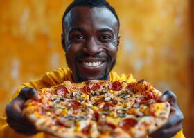 glücklich Mann ist halten köstlich Pizza im seine Hände und lächelnd während Stehen gegen Gelb Hintergrund foto