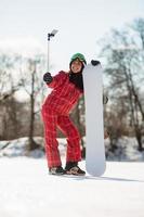 Frau mit dem Snowboard mit Smartphone auf einem Stock, um Selfie zu machen foto