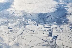 luftaufnahme über wolkenoberseite zu schneebedeckten flüssen, feldern und straßen, winterfrische frostige luft foto