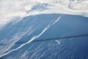 Antenne Aussicht von Flugzeug Fenster Über Wolken zu gefroren Meer mit Norden Dampf Gas Pipeline unter Wasser foto