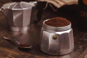 Moka Kaffee Topf gefüllt mit braun Boden Kaffee auf dunkel hölzern Planke, bereiten zu brauen Italienisch Espresso. foto