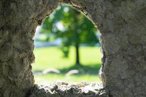 Steinhintergrund mit Fenster und Blick auf den verschwommenen grünen Baum. foto