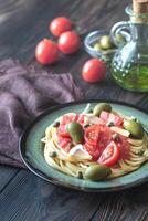 Pasta mit Tomate Soße, Oliven und Kapern auf das Teller foto